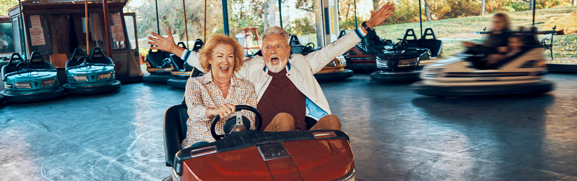Older cataract surgery couple riding in a bumper car
