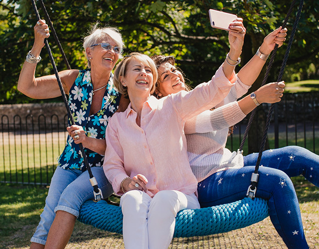 Cataract surgery patient on swing with friends taking selfies